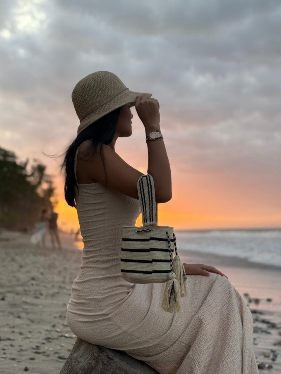 A woman carrying a black and cream woven bag at the beach