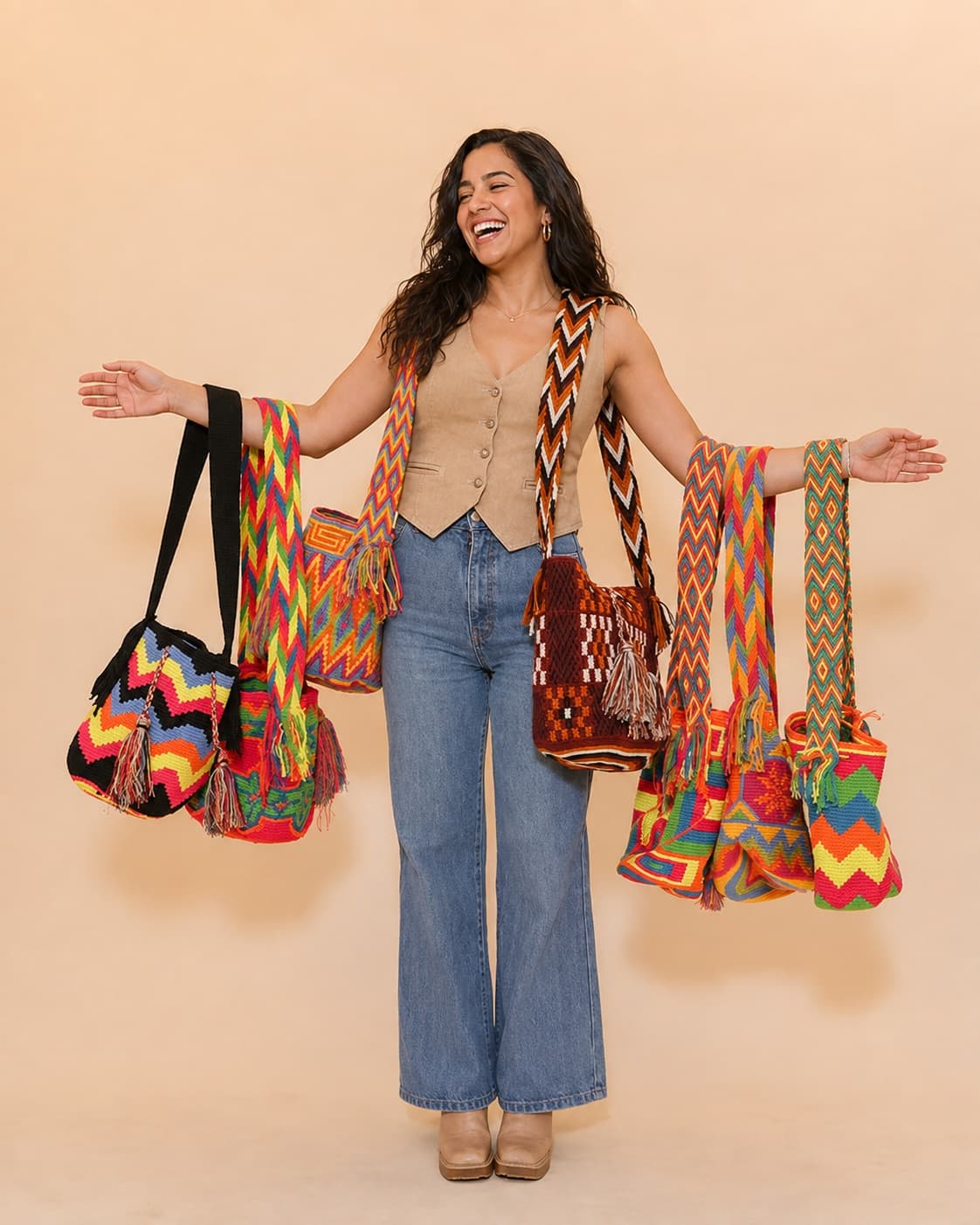 A joyful Latina woman carrying a collection of colorful handwoven Wayuu bags